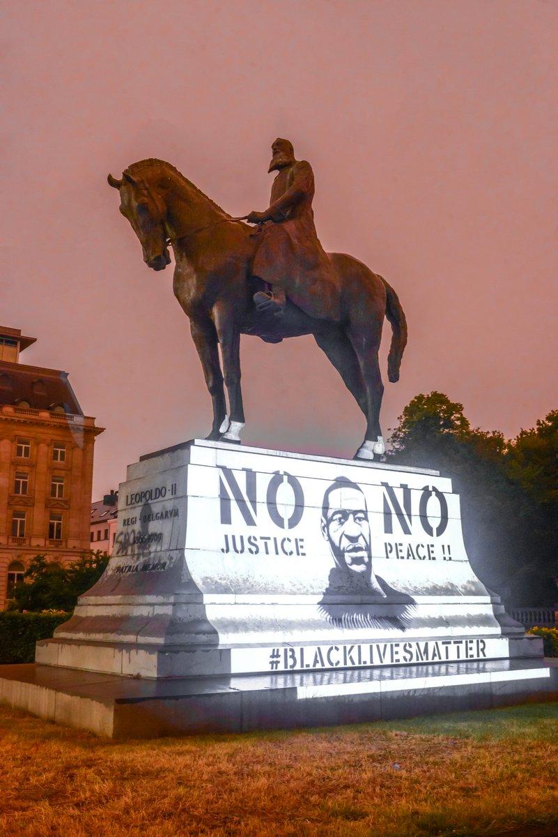 Statue de leopold ii illumine par un portrait de georges floyd